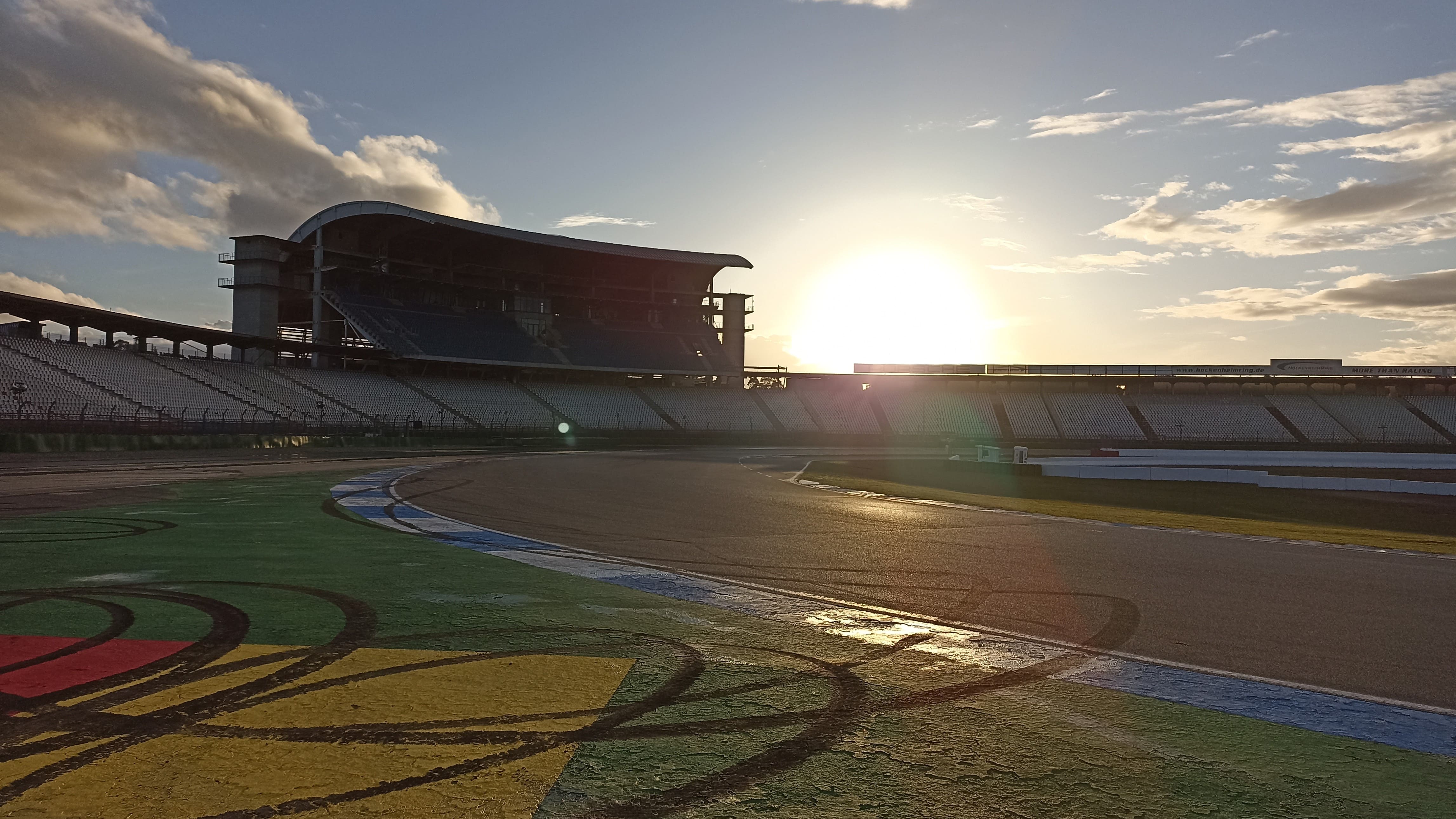 Ansicht der Rennstrecke des Hockenheimrings mit Zuschauertribüne im Hintergrund bei Sonnenuntergang