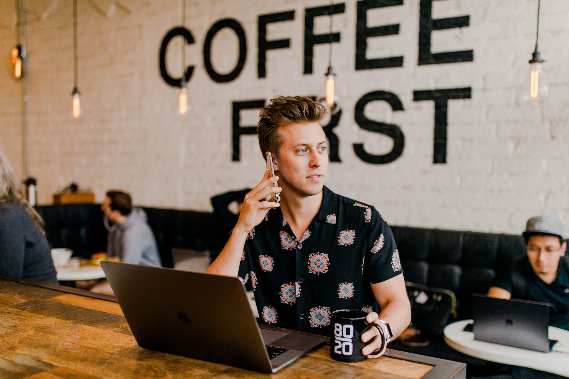 Stockfoto eines jungen Start-up-Gründers mit PC und Smartphone und einem Kaffee