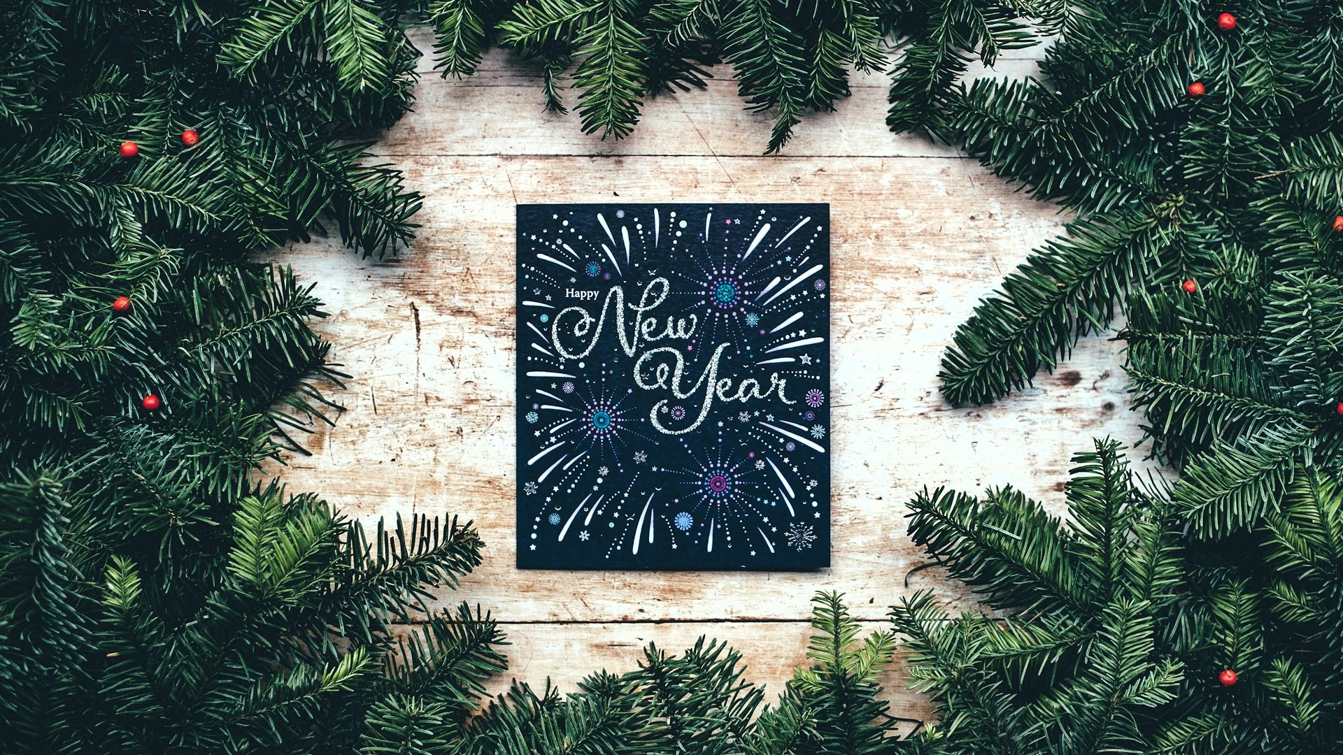 Symbolbild Tannenzweige und eine Neujahreskarte auf einem Holztisch zu Silvester 2023
