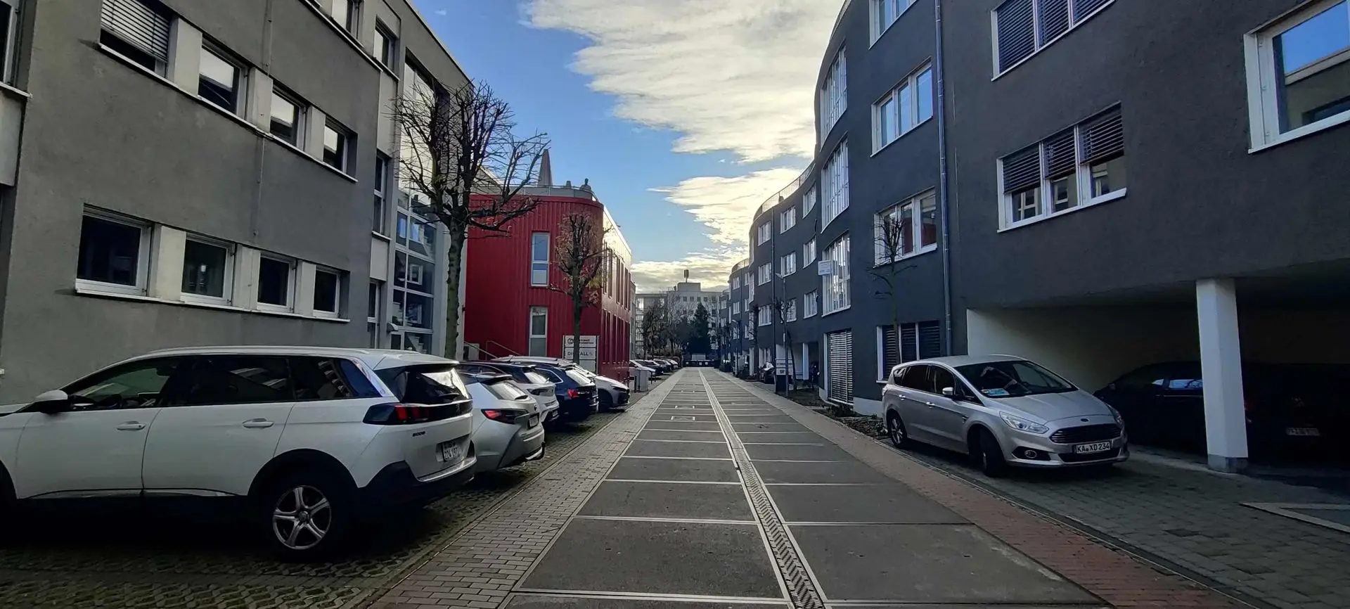 Titelbild mit der Überschrift "ready2charge". abgebildet ist eine Straße im Gewerbegebiet, am bildrand sieht man: Hier tanken Autos unseren Grünstrom