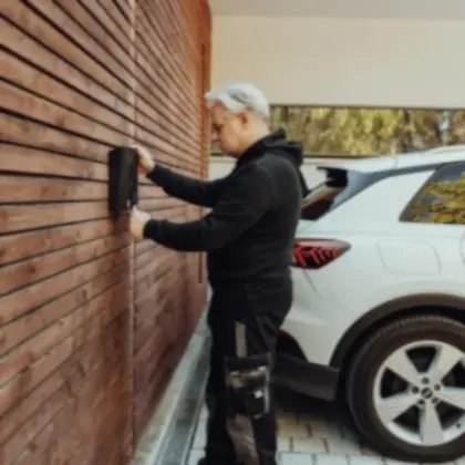 Person am Einfamilienhaus, die eine Wallbox betätigt