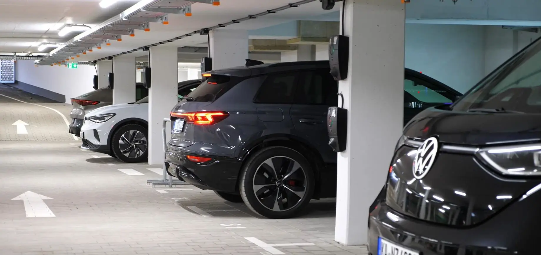 Foto einer Tiefgarage eines Mehrfamilienhauses, in dem Wallboxen und Leitungen ideal verlegt sind. Im Hintergrund parkende Autos und eine Ausfahrt.